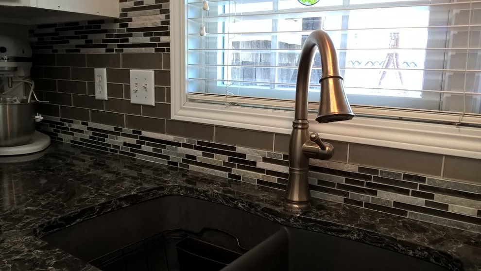 Example of a transitional kitchen design with a double-bowl sink, raised-panel cabinets, white cabinets, granite countertops, multicolored backsplash, glass tile backsplash and stainless steel appliances