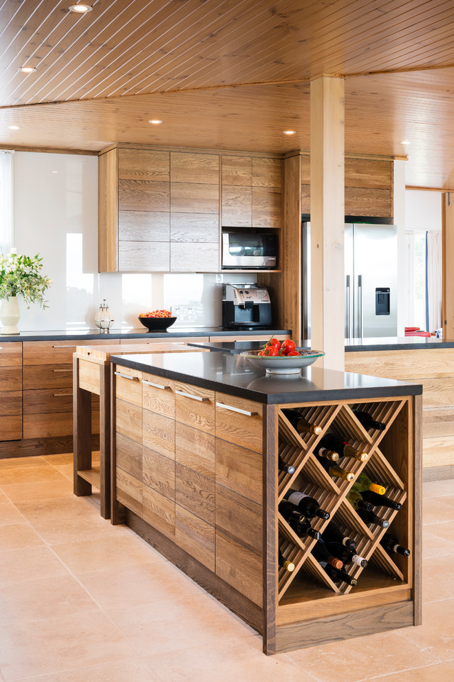 Large modern open plan kitchen in Melbourne with flat-panel cabinets, medium wood cabinets, multiple islands, quartz benchtops, white splashback, glass sheet splashback, stainless steel appliances and terra-cotta floors.