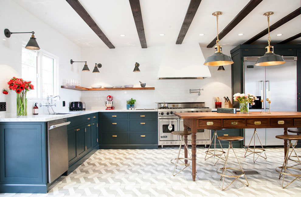 Example of a transitional l-shaped kitchen design with an undermount sink, blue cabinets, white backsplash, subway tile backsplash, stainless steel appliances and an island