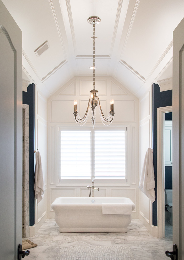 Photo of an expansive traditional master wet room bathroom in Austin with beaded inset cabinets, white cabinets, a freestanding tub, a two-piece toilet, white walls, marble floors, grey floor and a hinged shower door.
