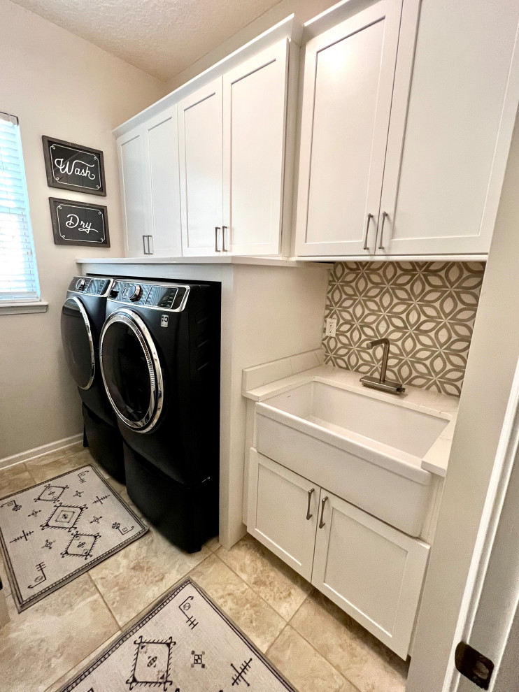 高級な中くらいなカントリー風のおしゃれな洗濯室 (I型、エプロンフロントシンク、落し込みパネル扉のキャビネット、白いキャビネット、クオーツストーンカウンター、グレーのキッチンパネル、セラミックタイルのキッチンパネル、ベージュの壁、大理石の床、左右配置の洗濯機・乾燥機、ベージュの床、白いキッチンカウンター) の写真