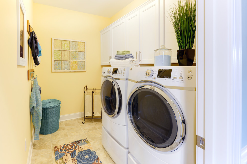 Photo of a beach style laundry room in Other with white cabinets, yellow walls and recessed-panel cabinets.