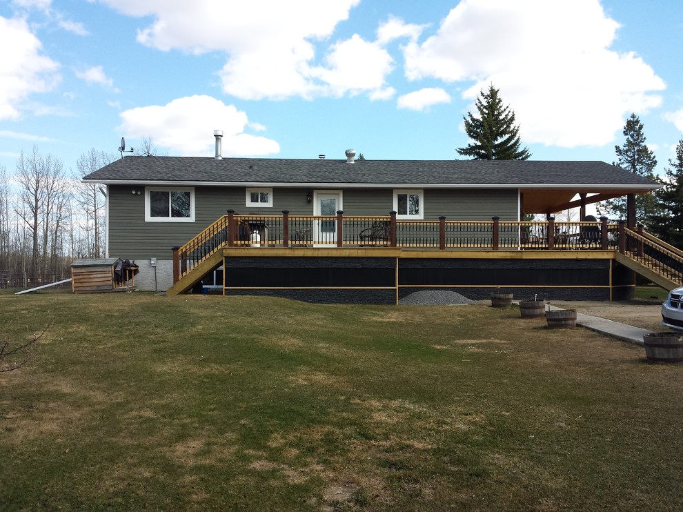 Mid-sized mountain style backyard deck photo in Edmonton with a roof extension