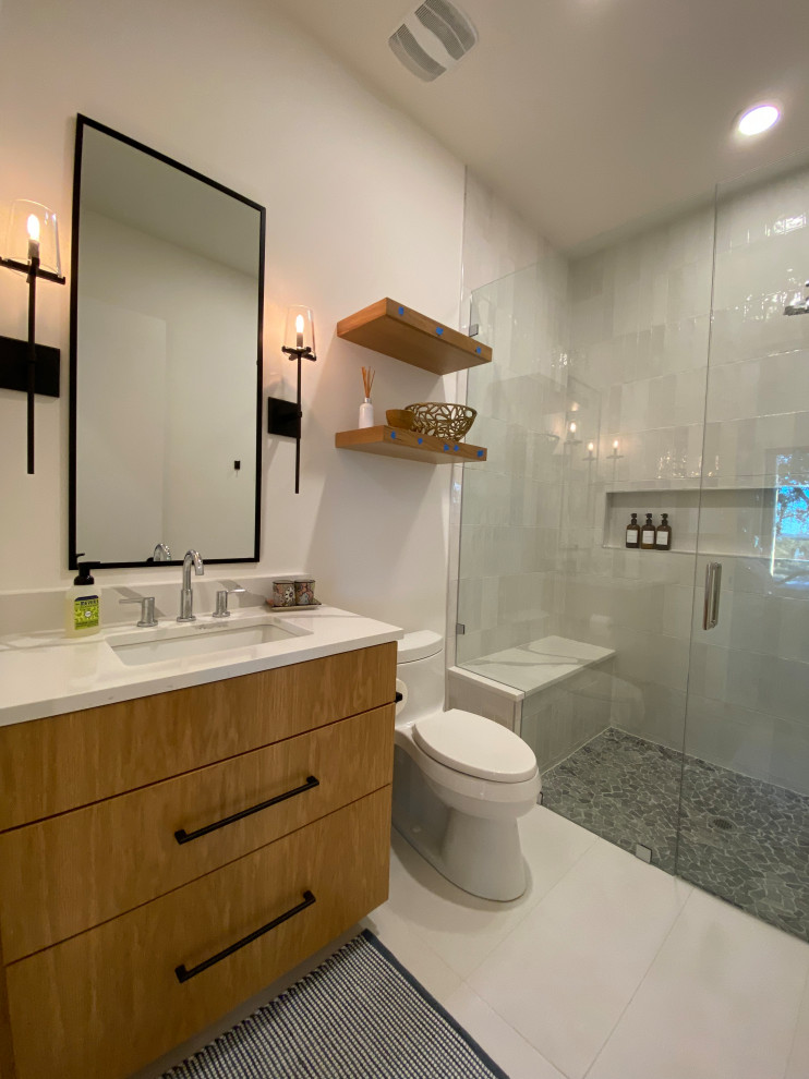 Mid-sized modern 3/4 bathroom in Austin with flat-panel cabinets, light wood cabinets, a curbless shower, a one-piece toilet, white tile, ceramic tile, white walls, porcelain floors, an undermount sink, engineered quartz benchtops, white floor, a hinged shower door, white benchtops, a shower seat, a single vanity and a built-in vanity.