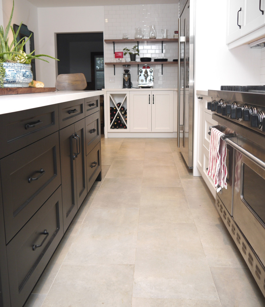 Example of a mid-sized transitional l-shaped porcelain tile and gray floor enclosed kitchen design in Toronto with a farmhouse sink, recessed-panel cabinets, white cabinets, quartz countertops, white backsplash, porcelain backsplash, stainless steel appliances, an island and white countertops