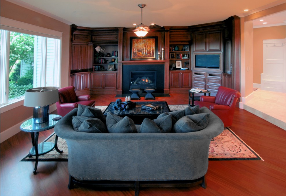 This is an example of a large traditional open concept family room in Portland with a music area, orange walls, medium hardwood floors, a standard fireplace, a stone fireplace surround, a built-in media wall and red floor.