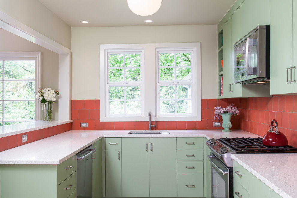 This is an example of a small transitional u-shaped eat-in kitchen in Portland with an undermount sink, flat-panel cabinets, green cabinets, recycled glass benchtops, orange splashback, ceramic splashback, stainless steel appliances and light hardwood floors.