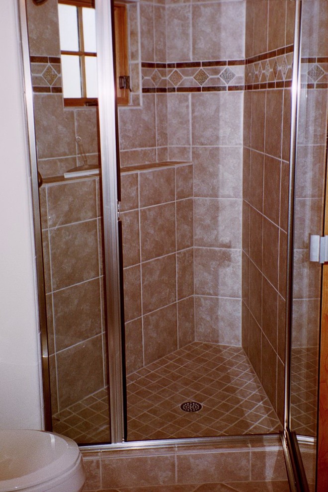 Alcove shower - transitional brown tile and porcelain tile alcove shower idea with a hinged shower door
