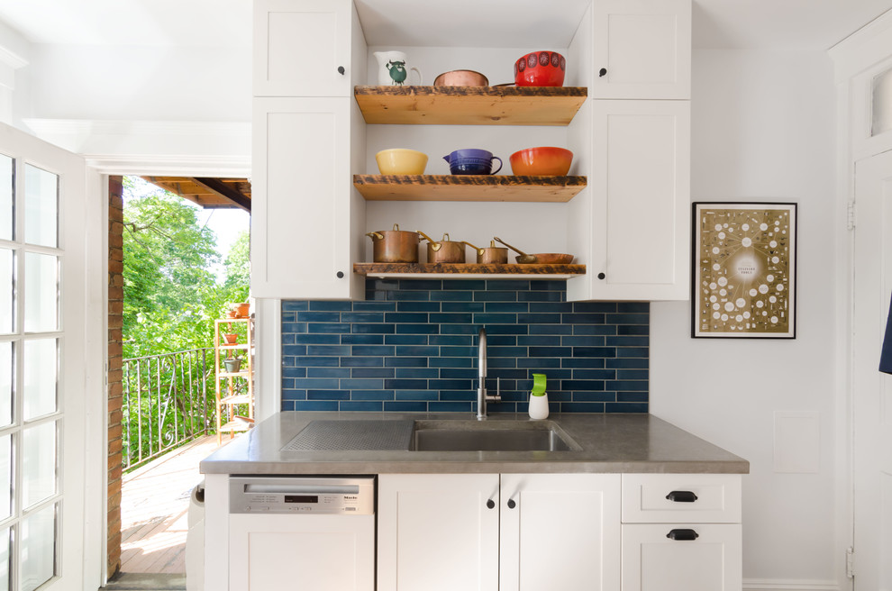 This is an example of a mid-sized eclectic u-shaped separate kitchen in Boston with an undermount sink, recessed-panel cabinets, white cabinets, concrete benchtops, blue splashback, subway tile splashback, white appliances, light hardwood floors, no island and brown floor.
