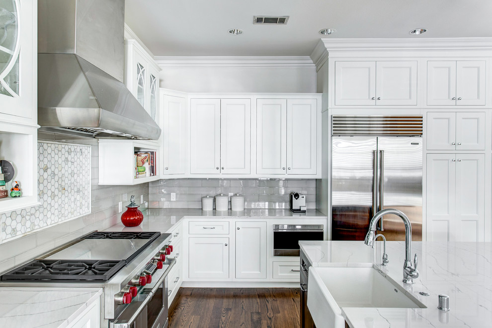 Design ideas for a large transitional l-shaped open plan kitchen in Dallas with a farmhouse sink, recessed-panel cabinets, white cabinets, quartz benchtops, grey splashback, ceramic splashback, stainless steel appliances, medium hardwood floors and with island.