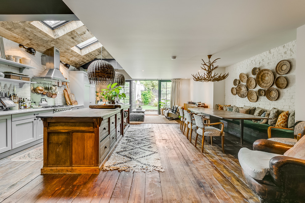 This is an example of an expansive eclectic open plan dining in London with white walls, medium hardwood floors and brown floor.