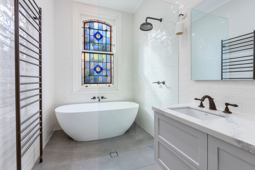 Inspiration for a mid-sized transitional master wet room bathroom in Melbourne with shaker cabinets, white cabinets, a freestanding tub, white tile, subway tile, white walls, porcelain floors, an undermount sink, engineered quartz benchtops, grey floor, an open shower, white benchtops, a double vanity and a floating vanity.