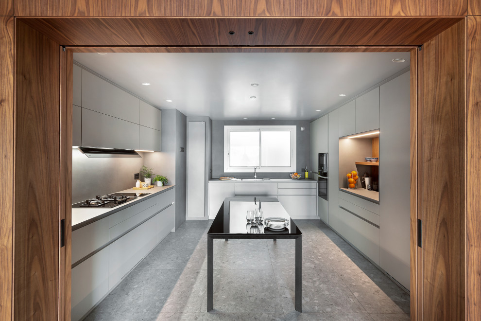 Moderne Küche in U-Form mit Unterbauwaschbecken, flächenbündigen Schrankfronten, grauen Schränken, schwarzen Elektrogeräten, grauem Boden, grauer Arbeitsplatte und Kücheninsel in Barcelona