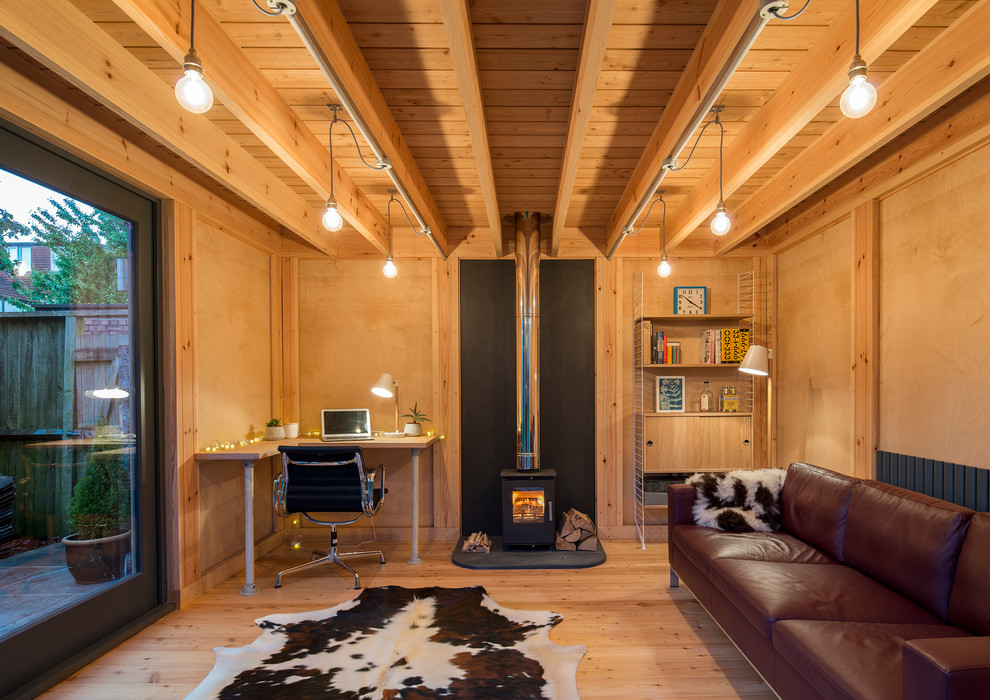 This is an example of a mid-sized scandinavian home studio in Other with a wood stove and a built-in desk.