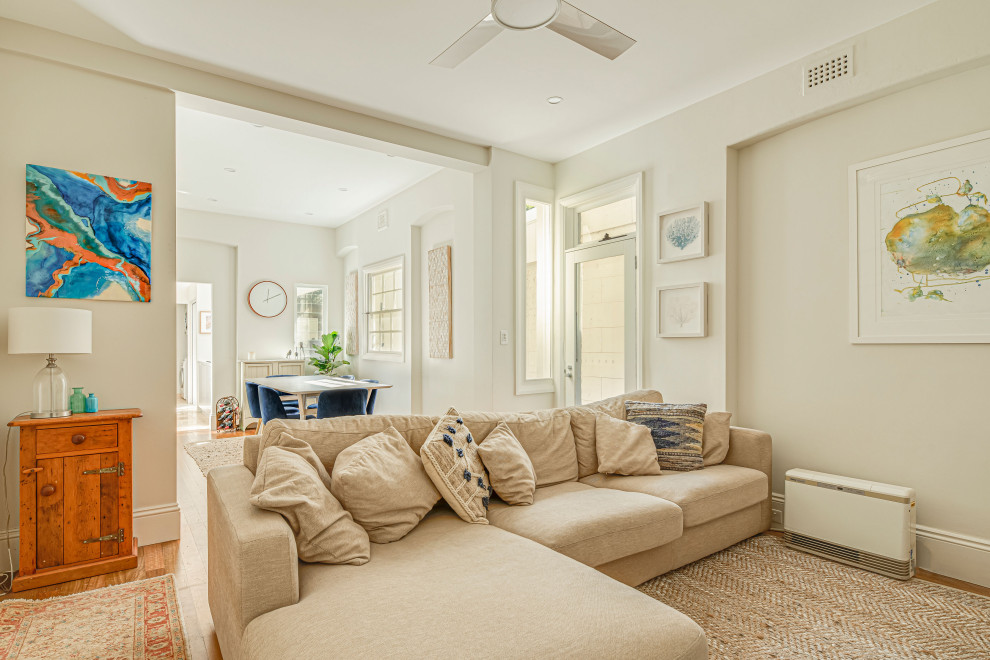 Contemporary open plan dining in Sydney with white walls, light hardwood floors and a standard fireplace.