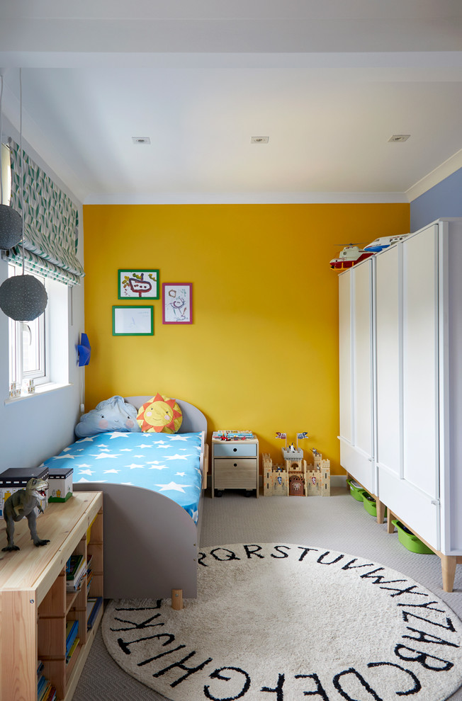 This is an example of a transitional gender-neutral toddler room in London with yellow walls, carpet and grey floor.