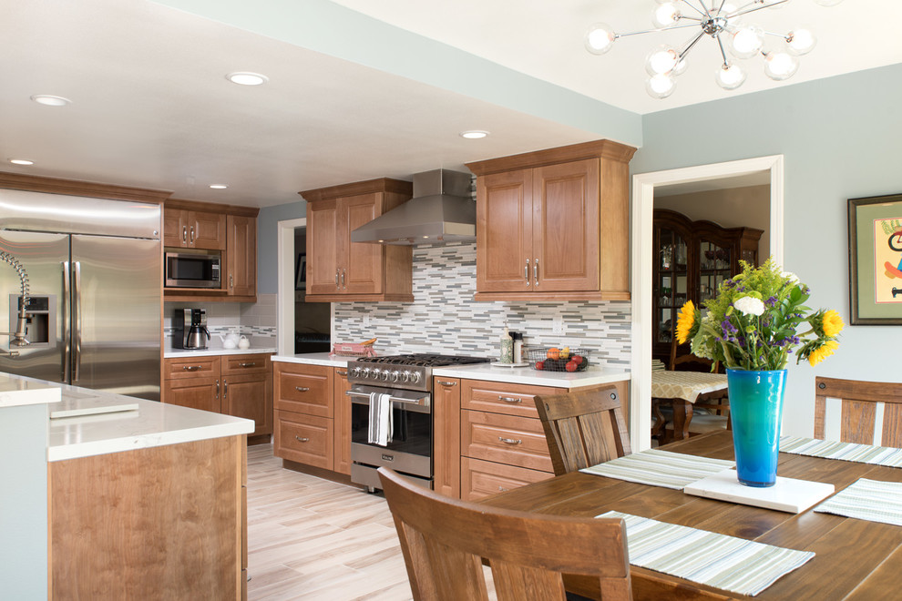 Large contemporary u-shaped eat-in kitchen in San Diego with a drop-in sink, raised-panel cabinets, medium wood cabinets, tile benchtops, grey splashback, glass tile splashback, stainless steel appliances and ceramic floors.