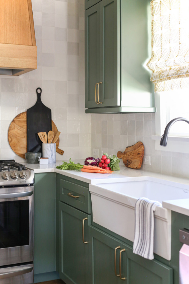 Klassisk inredning av ett litet vit vitt kök, med en rustik diskho, skåp i shakerstil, gröna skåp, bänkskiva i kvarts, vitt stänkskydd, stänkskydd i porslinskakel, rostfria vitvaror, mellanmörkt trägolv, en köksö och brunt golv