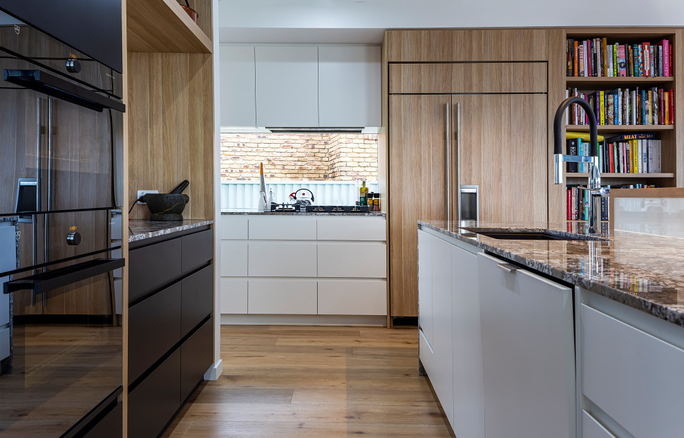 Photo of a contemporary u-shaped kitchen in Sunshine Coast with an undermount sink, flat-panel cabinets, white cabinets, window splashback, panelled appliances, medium hardwood floors, with island, brown floor and grey benchtop.