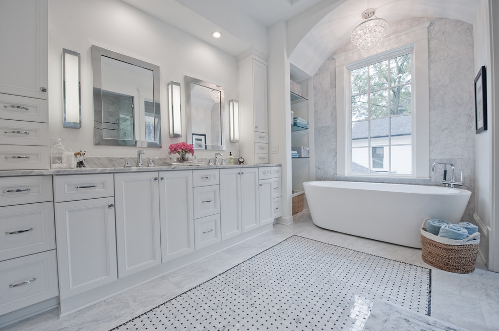 Photo of a large transitional master bathroom in Atlanta with white cabinets, marble benchtops, white tile, a freestanding tub, an undermount sink, white walls, marble floors, recessed-panel cabinets, grey floor, an alcove shower and a hinged shower door.
