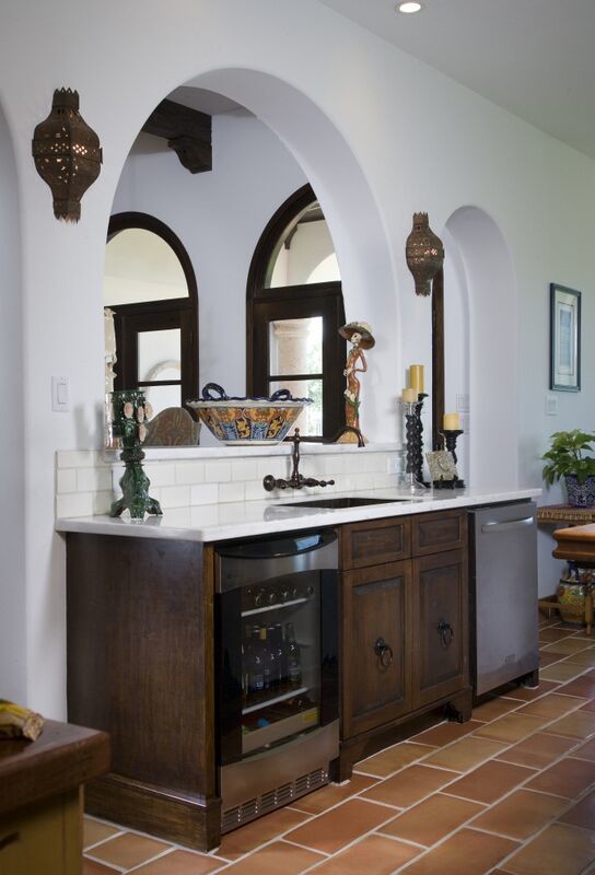 This is an example of a mid-sized mediterranean single-wall wet bar in Houston with an undermount sink, raised-panel cabinets, dark wood cabinets, white splashback, subway tile splashback, terra-cotta floors and brown floor.