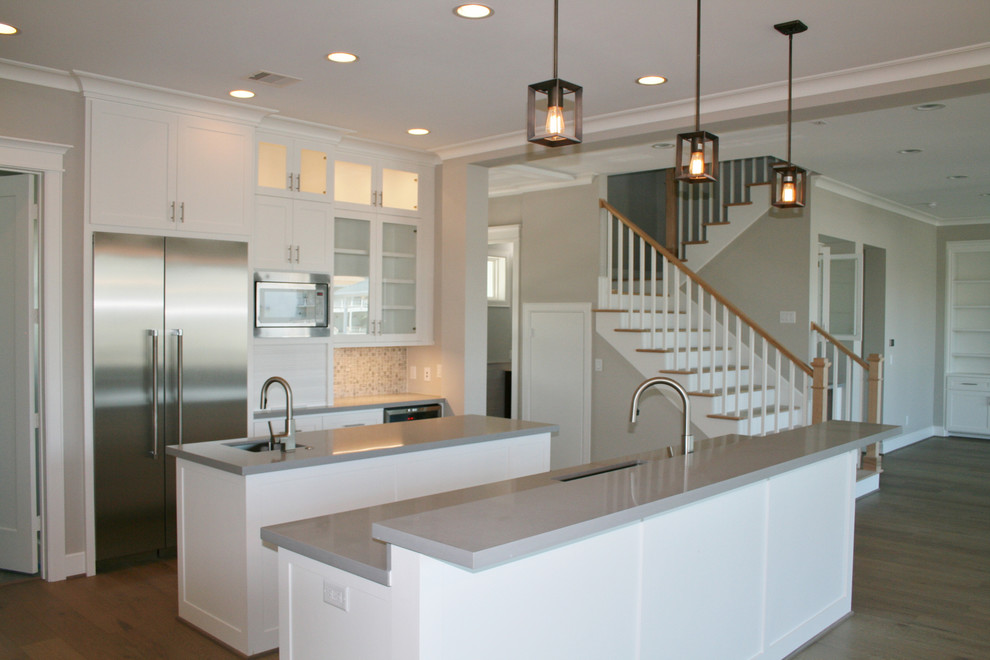 Inspiration for a large transitional l-shaped light wood floor and brown floor open concept kitchen remodel in Houston with an undermount sink, shaker cabinets, white cabinets, quartzite countertops, multicolored backsplash, mosaic tile backsplash, stainless steel appliances and two islands