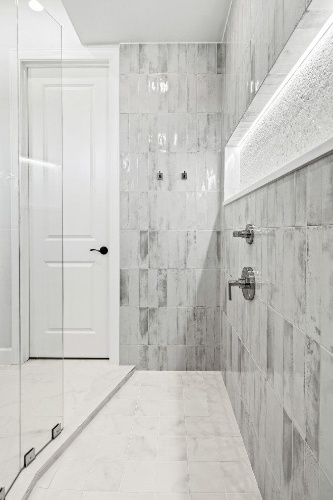 Example of a transitional master gray tile and porcelain tile porcelain tile, white floor and double-sink walk-in shower design with shaker cabinets, light wood cabinets, a two-piece toilet, white walls, an undermount sink, quartz countertops, white countertops, a niche and a built-in vanity