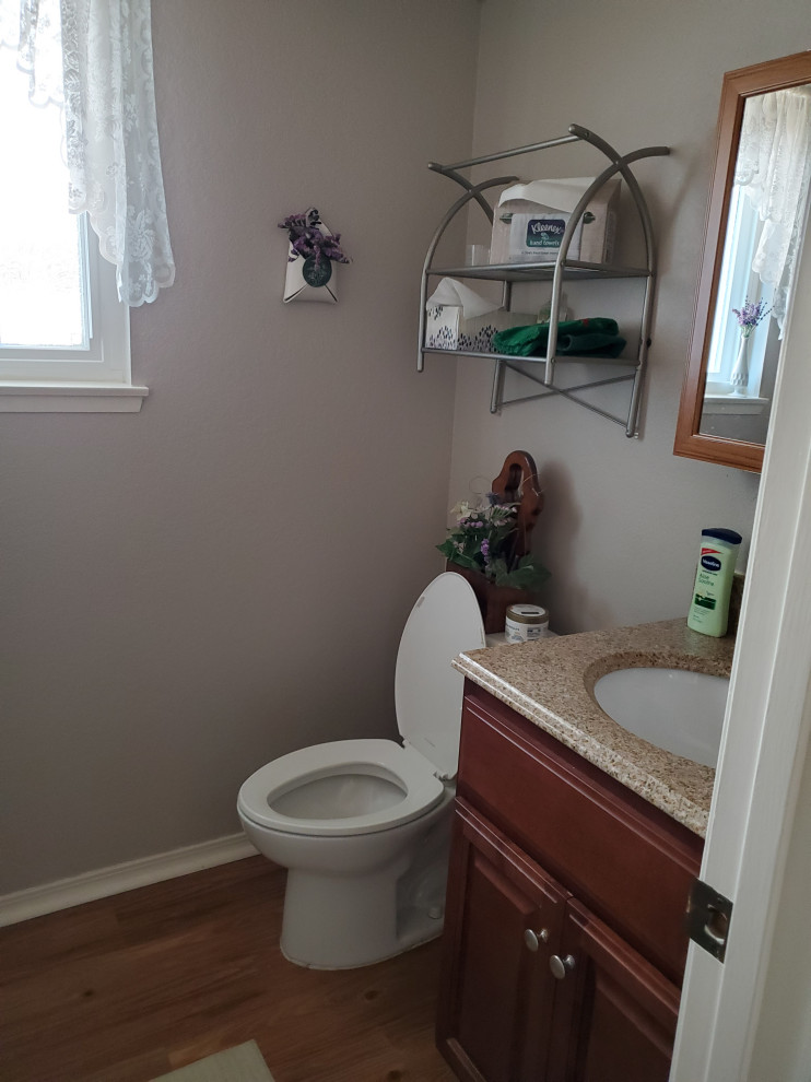Cette photo montre une petite salle de bain chic en bois foncé avec un placard avec porte à panneau surélevé, un sol en vinyl, un lavabo encastré, un plan de toilette en granite, un plan de toilette marron, meuble simple vasque et meuble-lavabo sur pied.