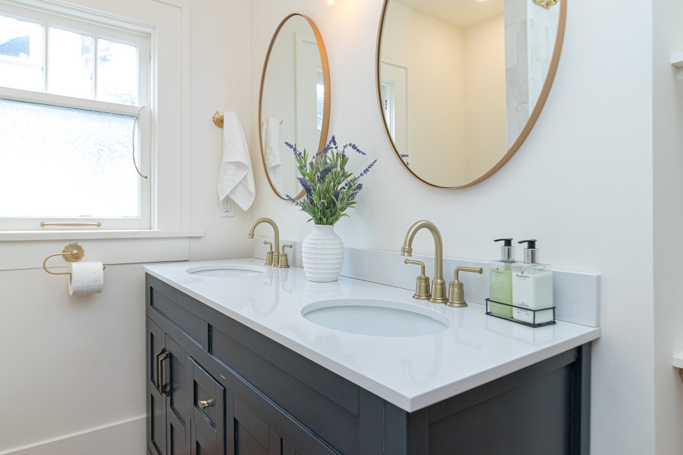Small transitional white tile beige floor and double-sink tub/shower combo photo with shaker cabinets, blue cabinets, a two-piece toilet, white walls, an undermount sink, soapstone countertops, white countertops and a freestanding vanity