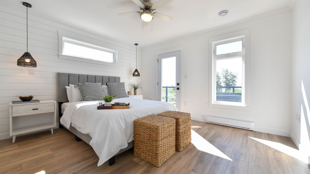 This is an example of a medium sized coastal guest bedroom in Other with white walls, laminate floors, brown floors and tongue and groove walls.