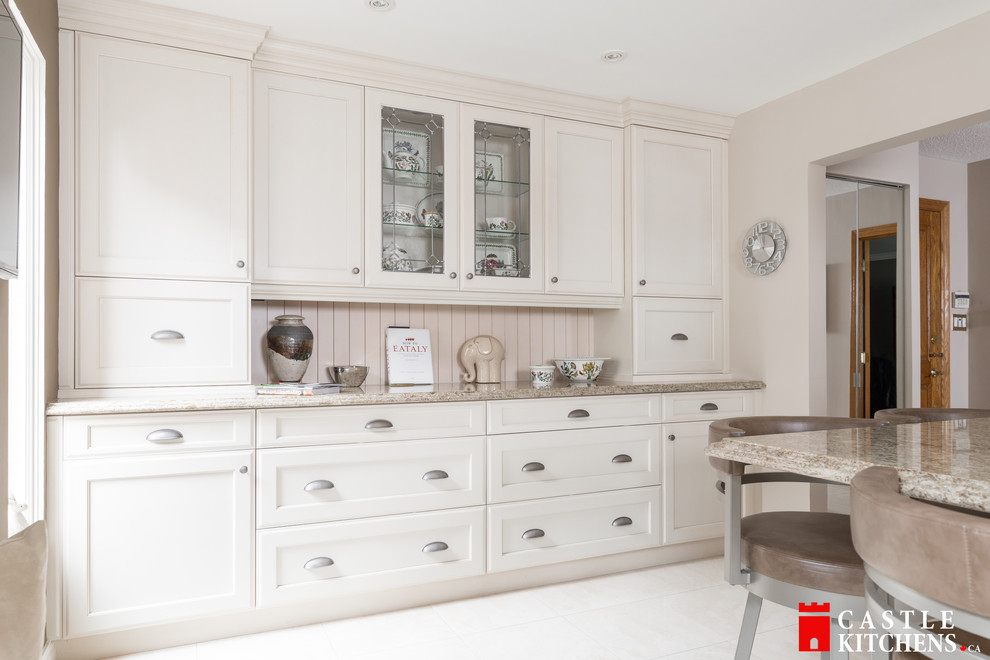 Enclosed kitchen - mid-sized transitional galley porcelain tile enclosed kitchen idea in Toronto with an undermount sink, shaker cabinets, beige cabinets, quartzite countertops, beige backsplash, stainless steel appliances and an island