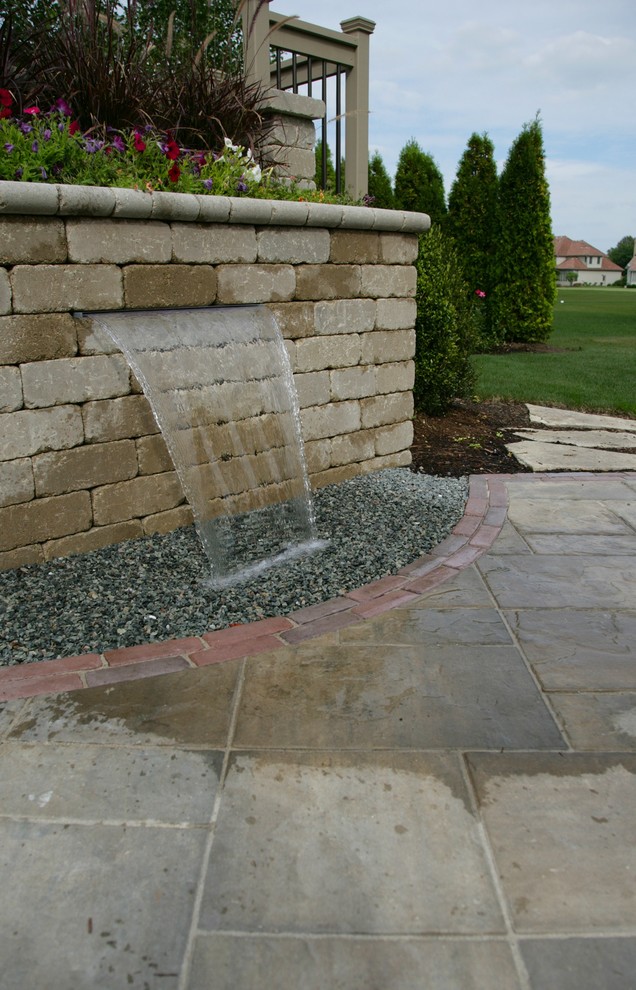 Photo of a large traditional backyard full sun garden for summer in Chicago with a water feature and brick pavers.