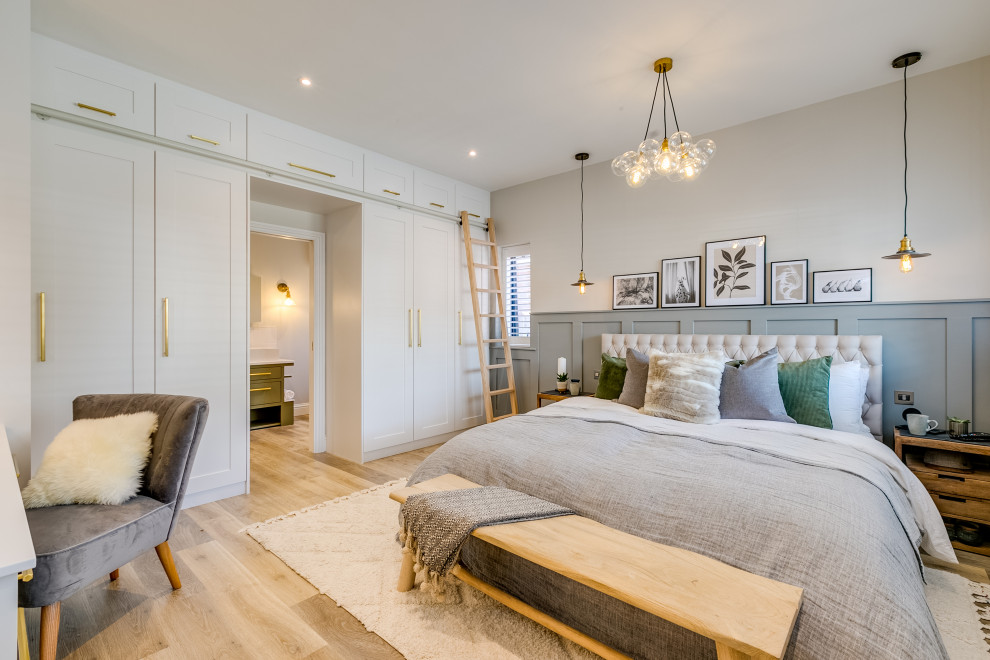 Diseño de dormitorio principal clásico renovado de tamaño medio sin chimenea con paredes grises, suelo laminado, suelo marrón y panelado
