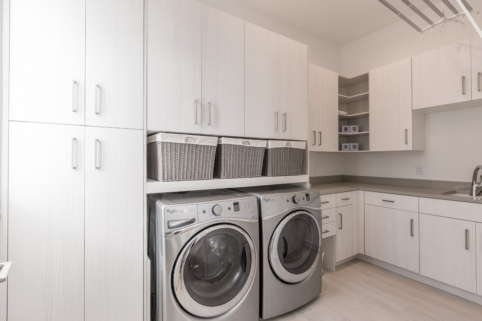 Mid-sized modern l-shaped dedicated laundry room in Charleston with an undermount sink, flat-panel cabinets, light hardwood floors and a side-by-side washer and dryer.