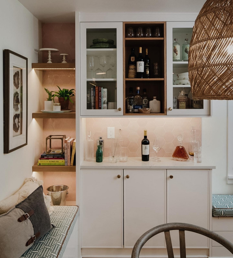 Photo of a small traditional l-shaped dry bar in Seattle with no sink, glass-front cabinets, white cabinets, engineered stone countertops, pink splashback, ceramic splashback, light hardwood flooring and white worktops.