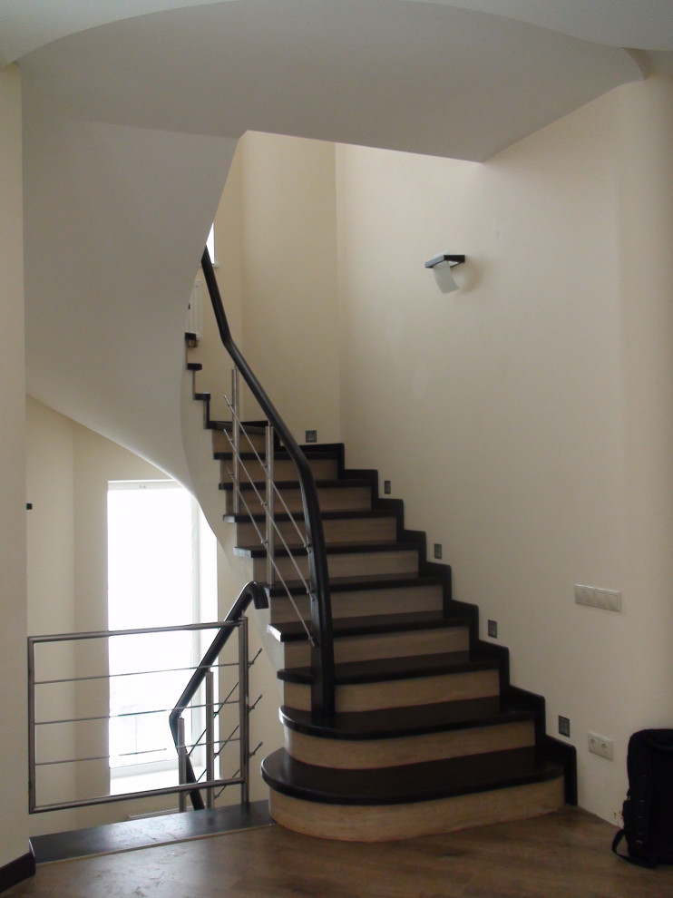 Стильный дизайн: изогнутая деревянная лестница среднего размера в стиле модернизм с деревянными ступенями, металлическими перилами и обоями на стенах - последний тренд