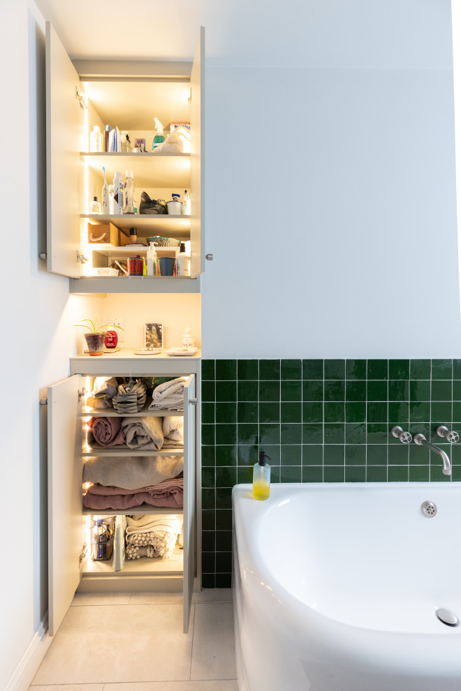 Mid-sized kids bathroom in London with a corner shower, green tile, white walls, ceramic floors, a wall-mount sink, grey floor, a sliding shower screen, a niche and a single vanity.