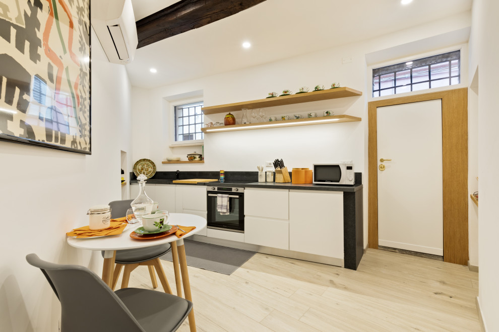 Photo of a small contemporary single-wall eat-in kitchen in Rome with a single-bowl sink, flat-panel cabinets, white cabinets, granite benchtops, grey splashback, granite splashback, stainless steel appliances, porcelain floors, no island, beige floor and grey benchtop.