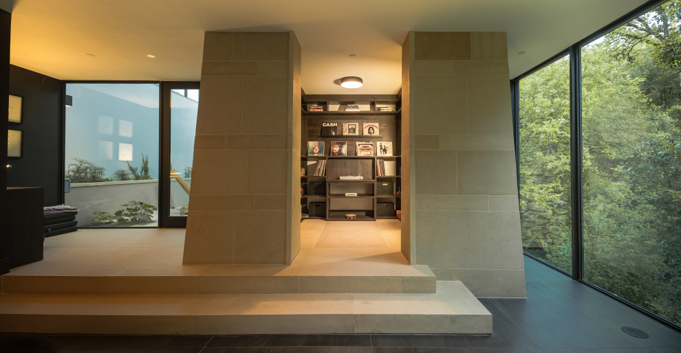 Свежая идея для дизайна: открытая гостиная комната среднего размера в стиле модернизм с с книжными шкафами и полками, черными стенами, полом из керамогранита и черным полом без камина, телевизора - отличное фото интерьера