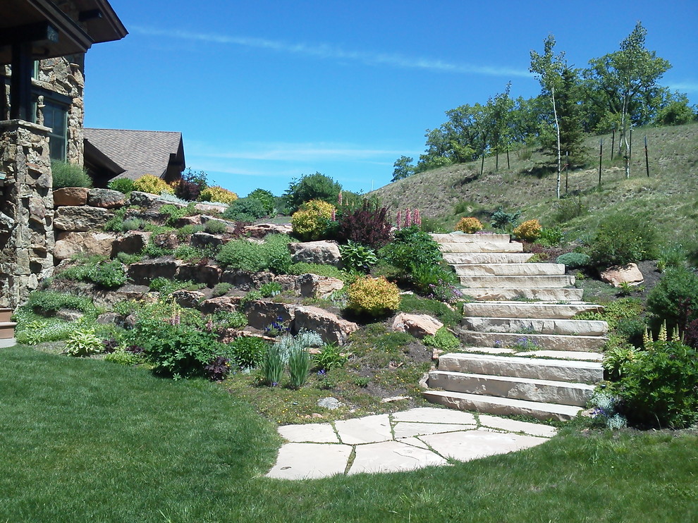 Photo of a large country front yard partial sun formal garden for spring in Denver with natural stone pavers and a garden path.