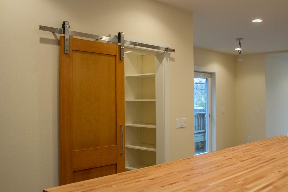 Mid-sized transitional galley light wood floor eat-in kitchen photo in Seattle with a drop-in sink, flat-panel cabinets, light wood cabinets, wood countertops, white backsplash, subway tile backsplash, stainless steel appliances and an island