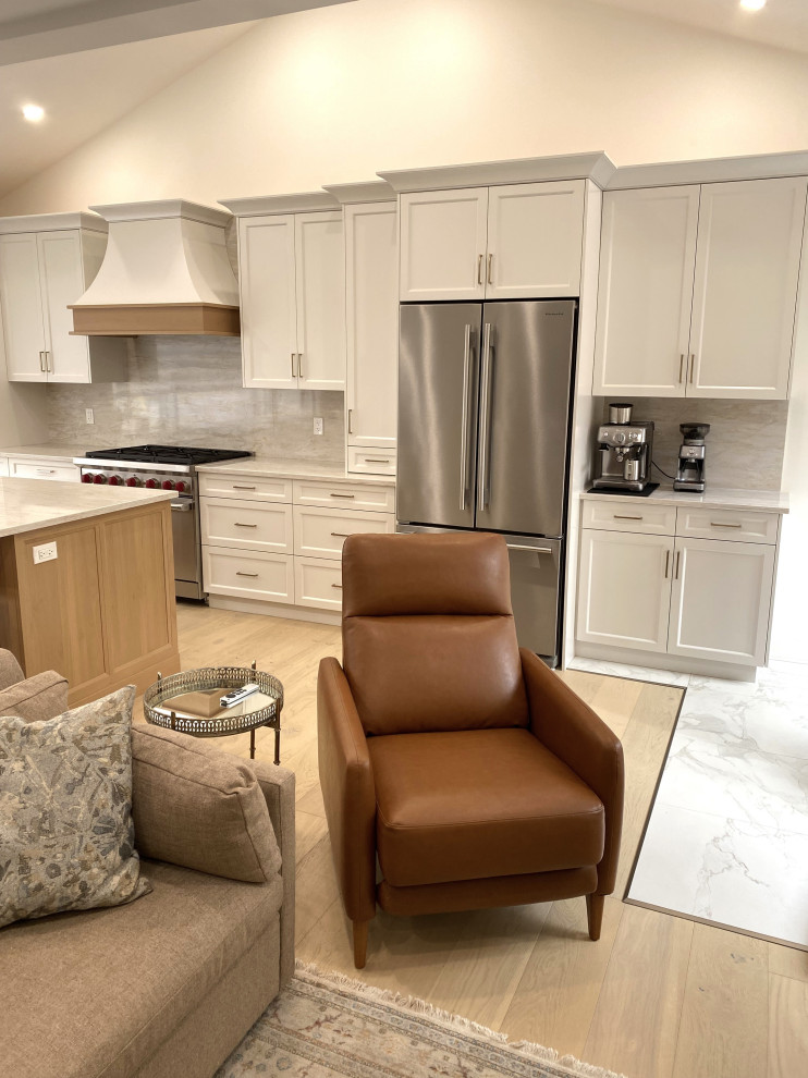 Small transitional galley light wood floor and vaulted ceiling open concept kitchen photo in Toronto with an undermount sink, recessed-panel cabinets, white cabinets, quartz countertops, quartz backsplash and stainless steel appliances