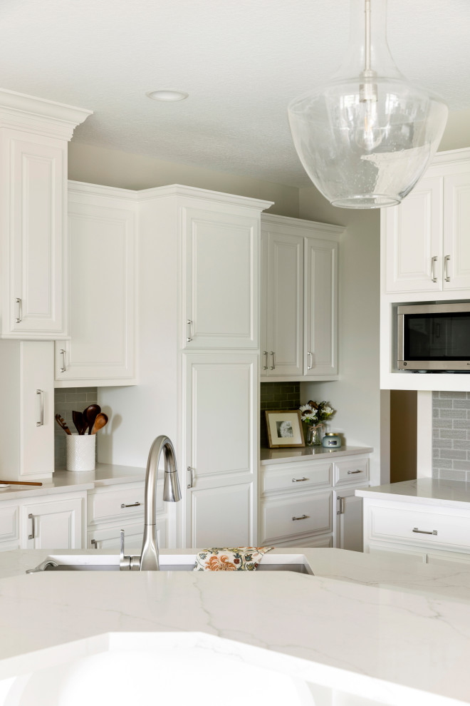 Inspiration for a mid-sized traditional l-shaped eat-in kitchen in Minneapolis with an undermount sink, raised-panel cabinets, white cabinets, quartzite benchtops, grey splashback, glass tile splashback, stainless steel appliances, dark hardwood floors, with island, brown floor and white benchtop.