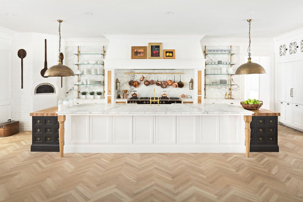 Inspiration for a traditional l-shaped kitchen in Salt Lake City with a farmhouse sink, recessed-panel cabinets, white splashback, black appliances, light hardwood floors, multiple islands, brown floor and white benchtop.