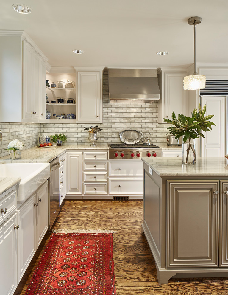 Design ideas for a traditional l-shaped kitchen in Dallas with a farmhouse sink, recessed-panel cabinets, white cabinets, grey splashback, stainless steel appliances, dark hardwood floors, with island, brown floor and grey benchtop.