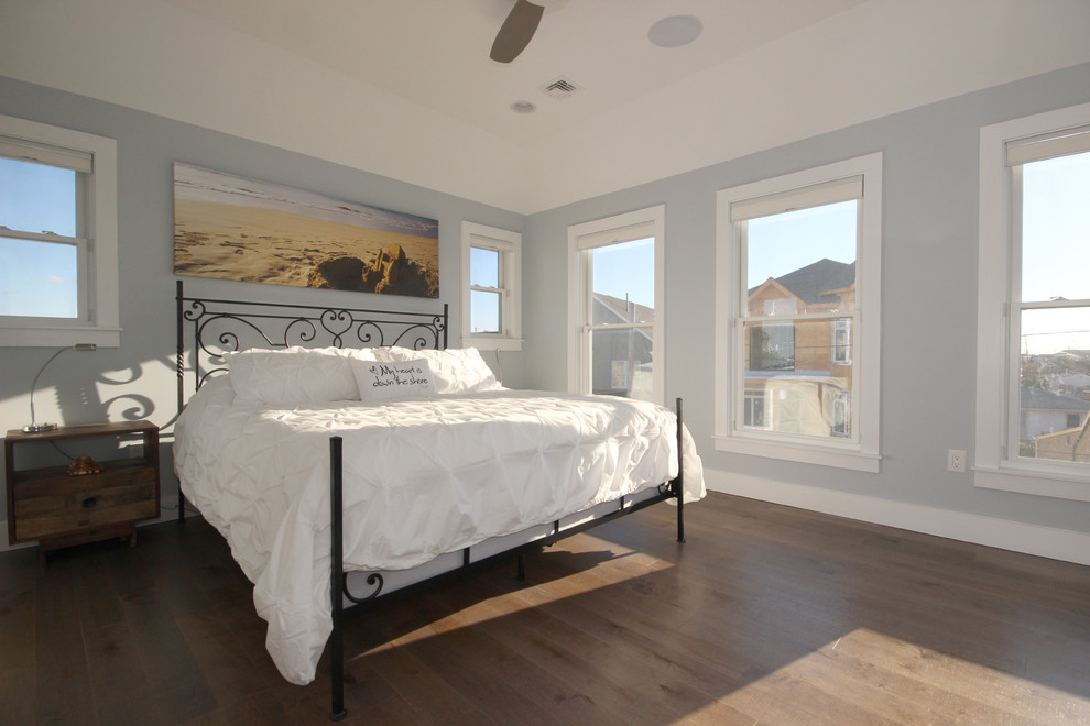 This is an example of a mid-sized beach style master bedroom in New York with grey walls, light hardwood floors, no fireplace and brown floor.