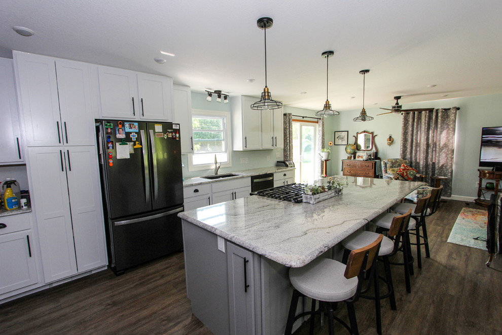 Inspiration for a mid-sized transitional single-wall laminate floor and brown floor open concept kitchen remodel in Minneapolis with an undermount sink, shaker cabinets, gray cabinets, granite countertops, stainless steel appliances, an island and gray countertops