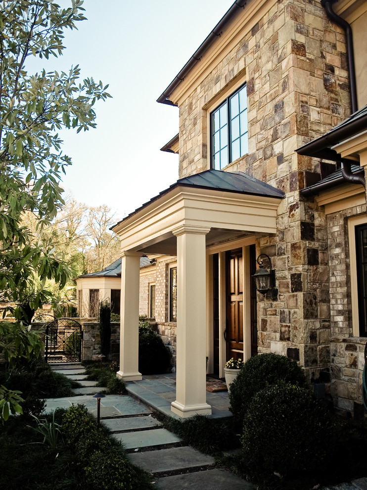 Design ideas for a mid-sized traditional two-storey beige house exterior in Atlanta with stone veneer, a hip roof and a metal roof.