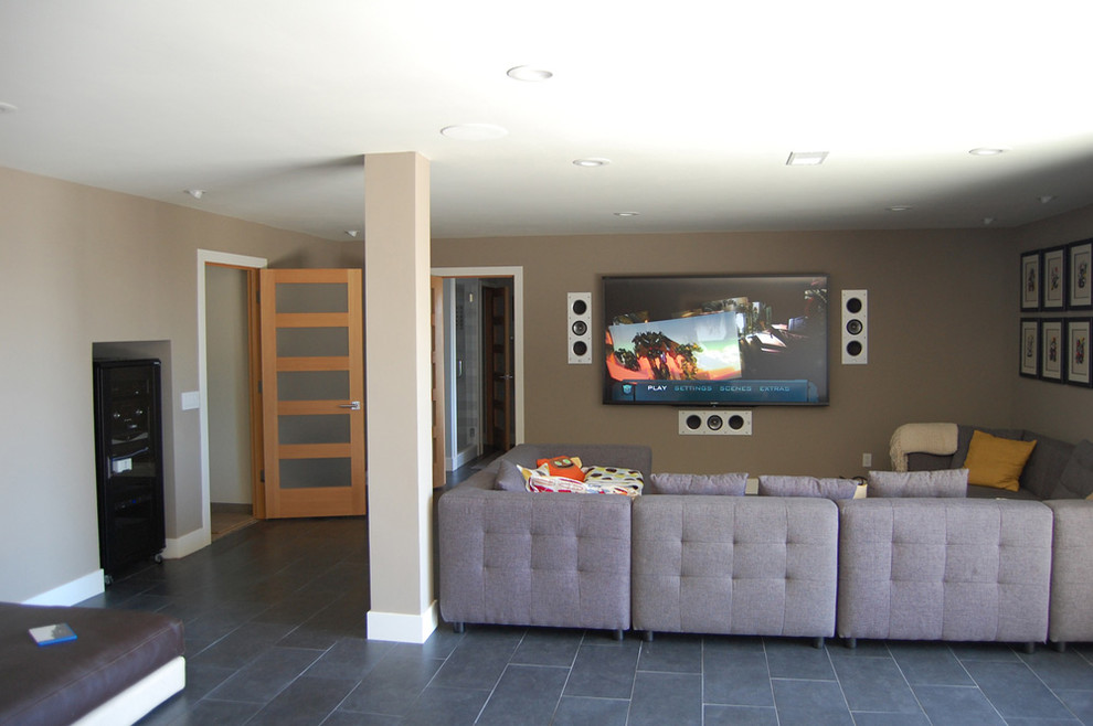 This is an example of a mid-sized open concept home theatre in Los Angeles with beige walls, slate floors and a wall-mounted tv.