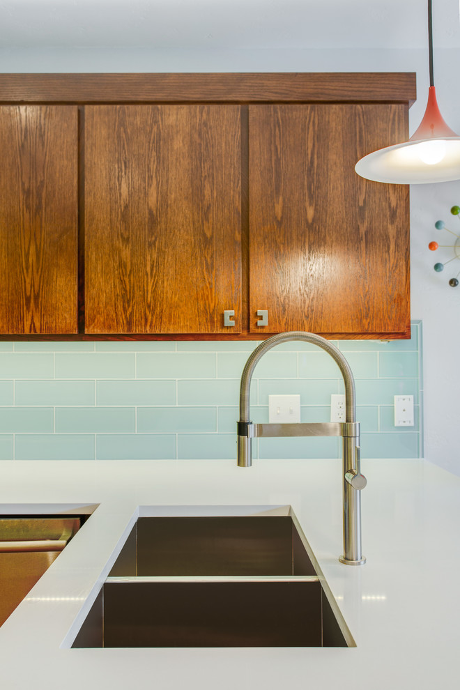 Design ideas for a mid-sized midcentury l-shaped eat-in kitchen in Dallas with an undermount sink, flat-panel cabinets, medium wood cabinets, quartz benchtops, blue splashback, glass tile splashback, stainless steel appliances, a peninsula and white benchtop.